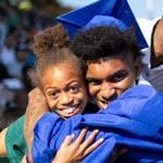 在毕业典礼上，一位戴着帽子的成年毕业生拥抱了一位更小的孩子.