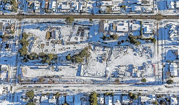 鸟瞰图，建筑工地被雪覆盖，上面是空旷的街道，周围是白雪覆盖的街道