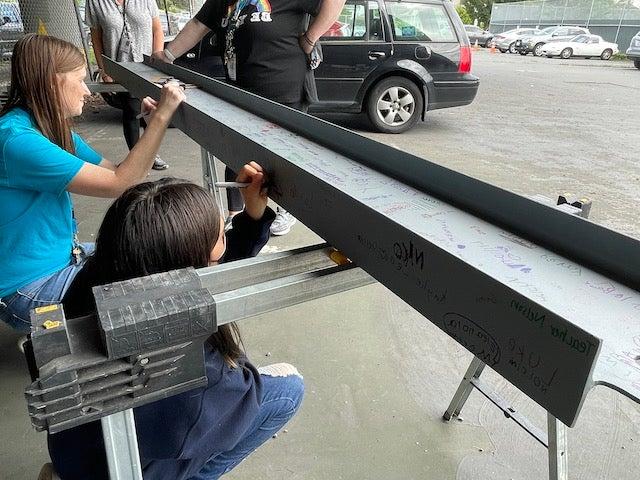 大人和小孩在外面的钢梁上签名