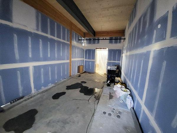 一个狭窄的房间，有墙板和墙板胶带，墙上有泥