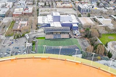 前景中弯曲的橙色表面俯视着运动场和下面的看台，外面是其他建筑