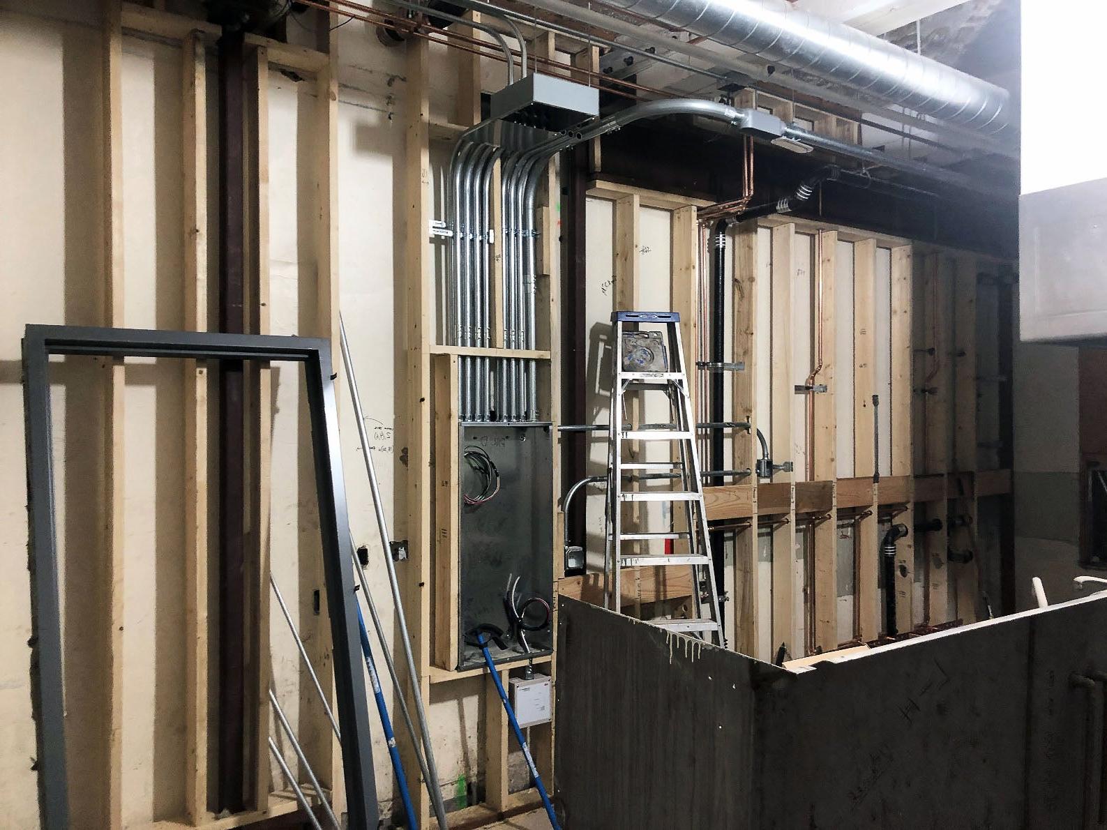 wood framing is open to the room with wallboard on the back side of it. piping, ducts, and electrical conduit can be seen in the walls
