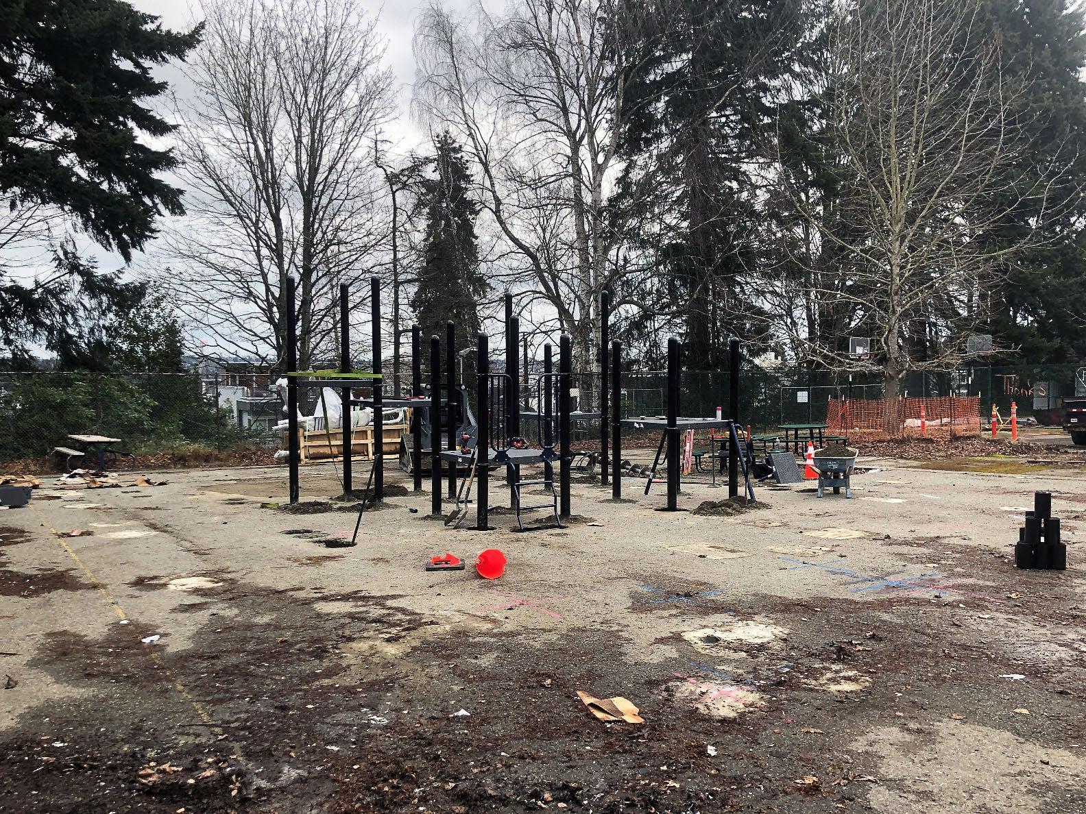 a concrete pad has part of a play structure installed. trees are in the background