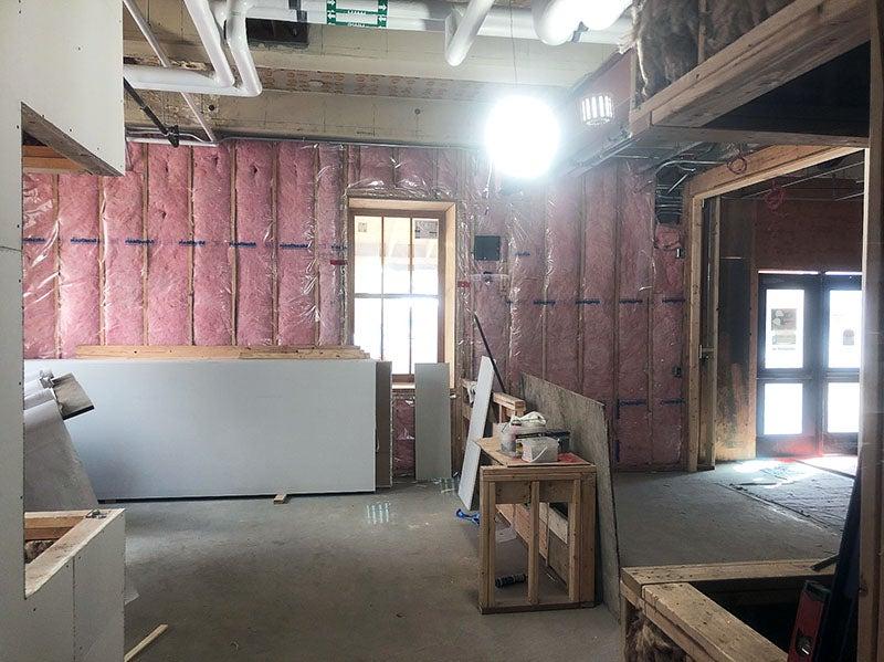 a room under construction has pink fluffy material between wall studs, a window to outside, and a partially built large box