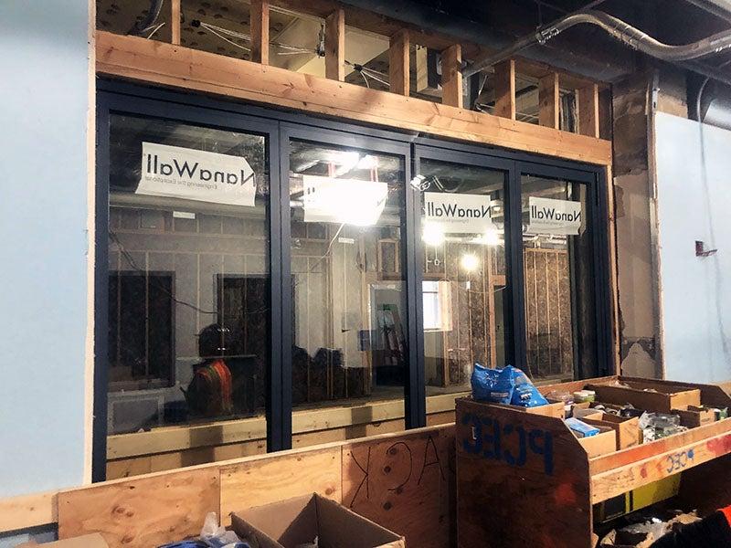 a room underconstruction has four glass panels with black framing between two walls. The glass says "nana wall."