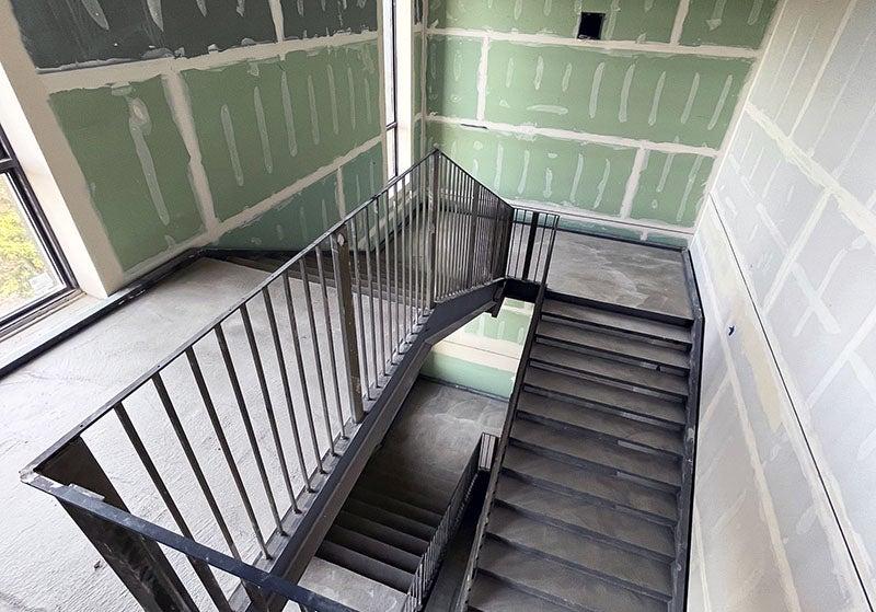 混凝土楼梯，绿色墙板上粘着胶带和泥