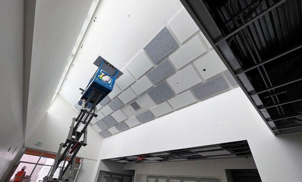一个人在一个有角度的天花板上安装天花板瓷砖