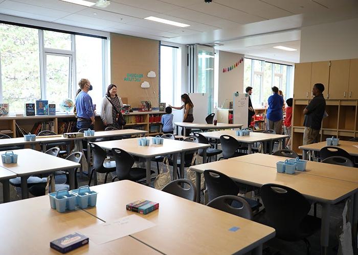 一间教室，有几组桌子和一面通往另一间教室的墙