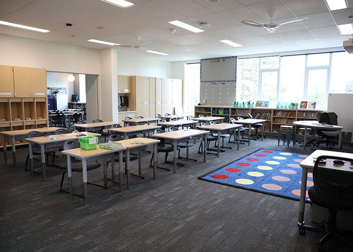 教室里有一排排的课桌，地毯上有彩色的圆圈