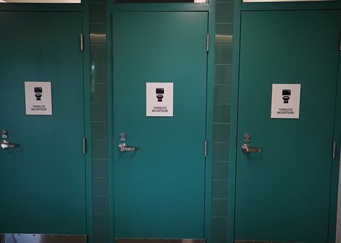 3扇蓝绿色的门上有一个厕所图标，上面写着学生厕所